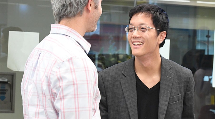 An alum smile and talks to a former instructor.