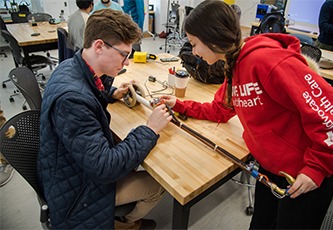 Two students work on a smart cane prototype in the design studio.
