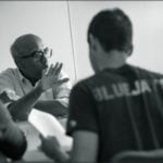 Tilak speaks with a group of students at a table.