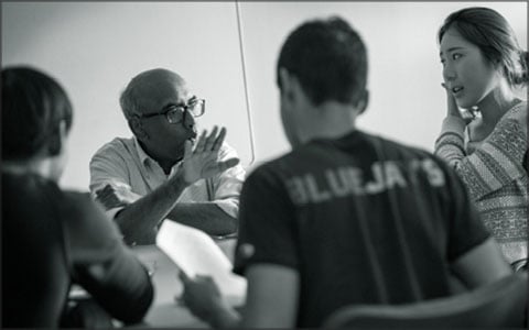 Tilak speaks with a group of students at a table.