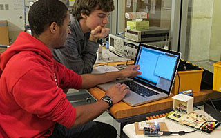 Two students work at a computer in the lab.
