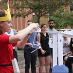 A female student dressed in a costume prepares to launch a ping pong ball down her design.