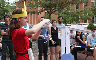 A female student dressed in a costume prepares to launch a ping pong ball down her design.