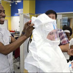 Student help another student try on a white ebola suit.