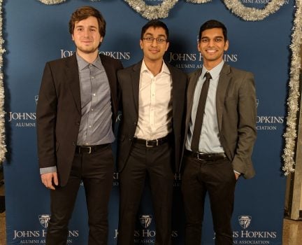 Three young men stand together for a photo.