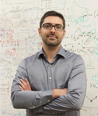 Mark Walker stands in front of a dry erase board with lots of equations.