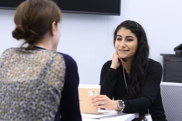 Two female students are talking at a table.