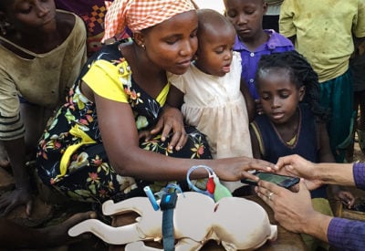 A mother from Uganda learns how to use a healthcare app on a smart phone.