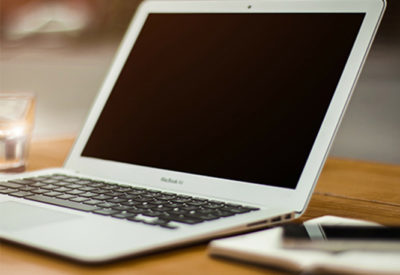 A laptop rests on a wood table.