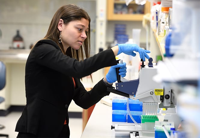 A young female faculty member works with pipettes in a wet lab.
