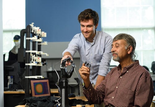 A student and a faculty member work with a prosthetic hand.