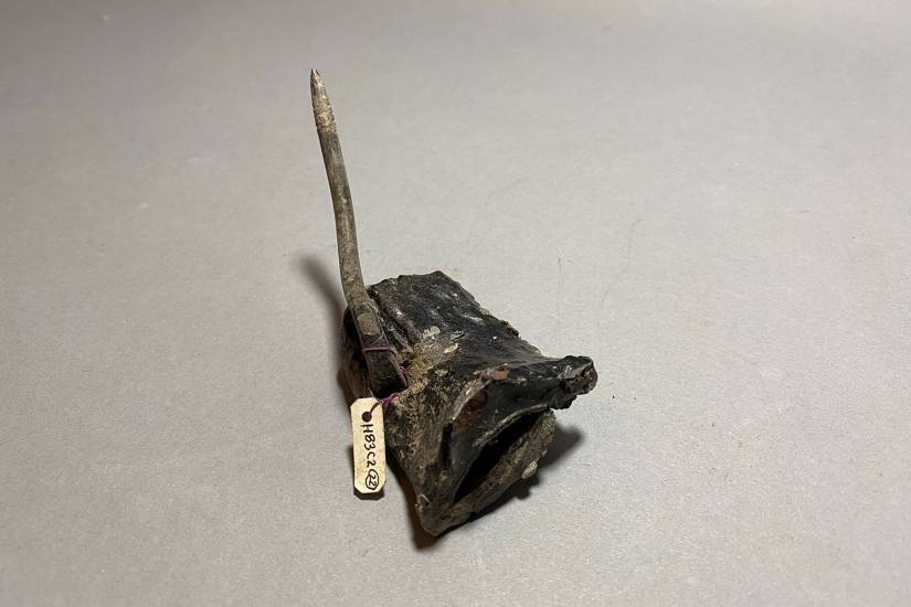 A pointy piece of scrap metal shows a small tag with numbers attached to it.
