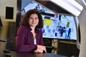 Sarah Capostagno smiles near a C-arm and a monitor.