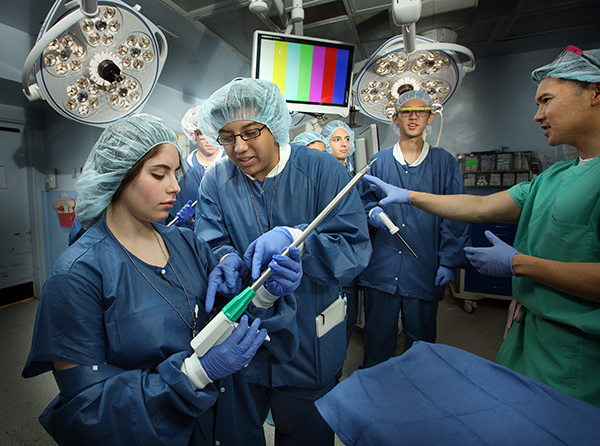 BME students are wearing scrubs working in the OR with medical devices.