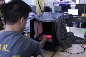 A student puts his hand inside a black box with a red light.