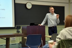 John Hickey stands at the front of a classroom as he teaches.