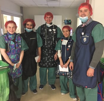 Students wearing scrubs stand together for a photo.