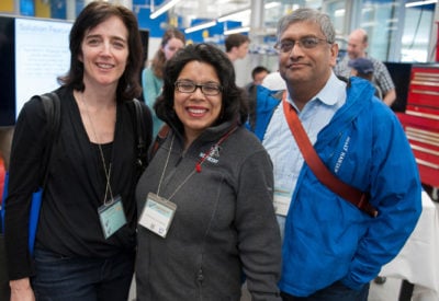 Three alumni stand together and smile for the camera.