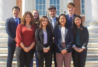 A group of students are dressed professionally and standing together on a set of outdoor stairs.