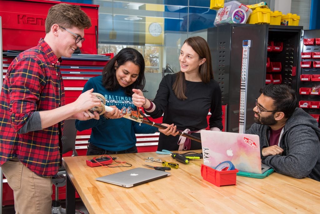 A group of students work with a faculty member on a prototype in the Design Studio.