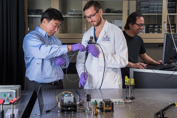 A faculty members works with a clinician on a medical device in the lab.