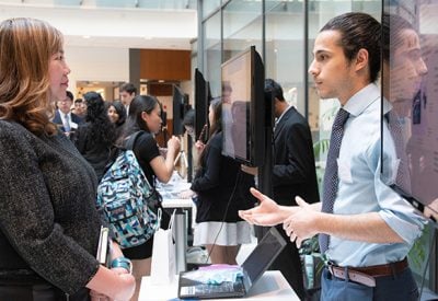 A student speaks with an industry partner in a large room.