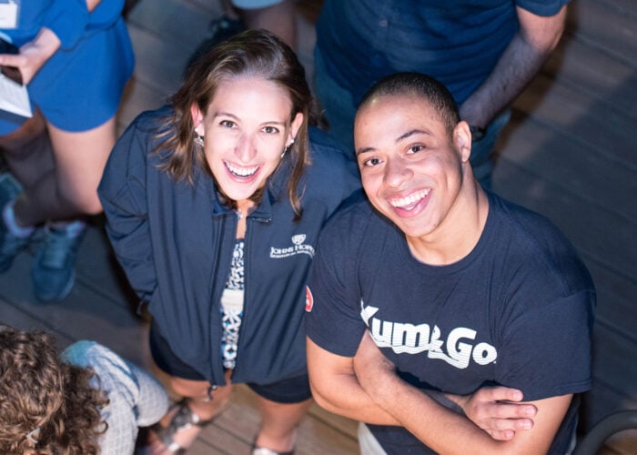 A female and a male graduate are smiling up at the camera.