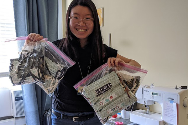 Ivy Wang is holding up two gallon bags filled with her homemade masks.