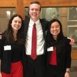 Three students stand together wearing a combination of red, white, and black clothing.