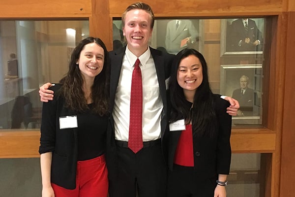 Three students stand together wearing a combination of red, white, and black clothing.