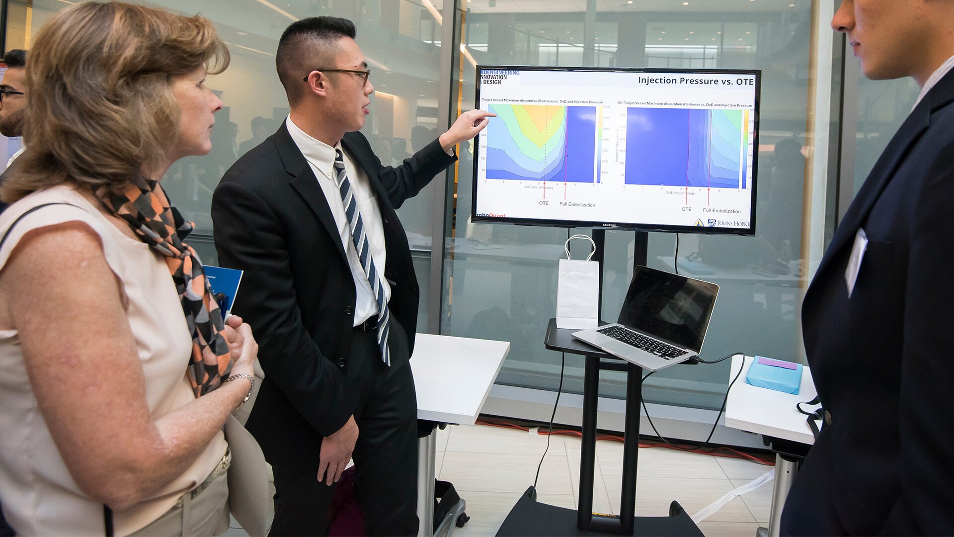 A student presents his project to two onlookers.