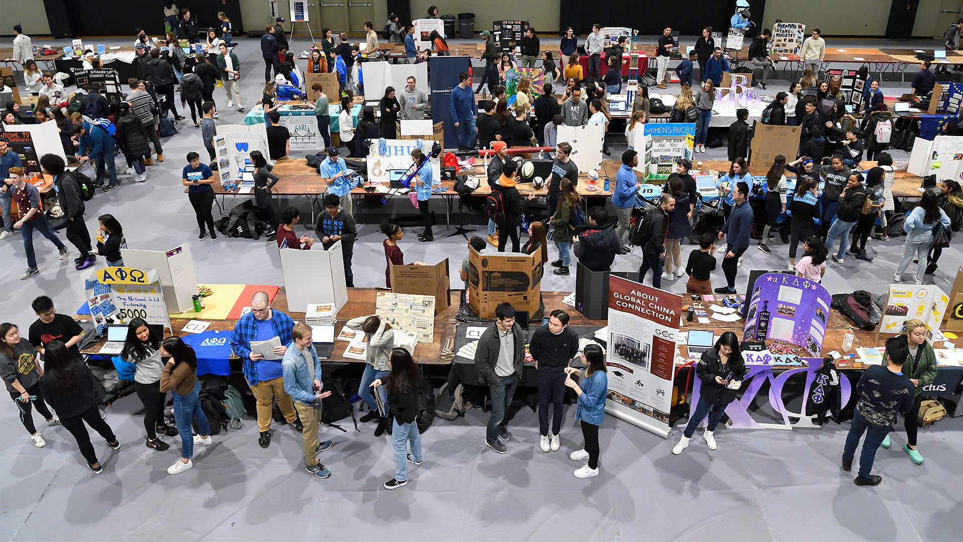 A wide shot of a large event with a lot of people in a gymnasium.