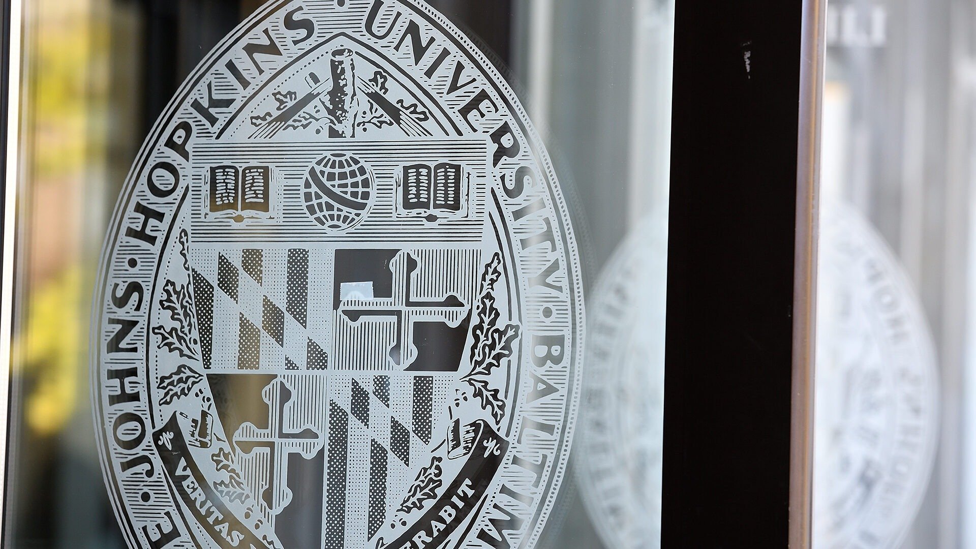 The JHU crest is shown on a glass door.