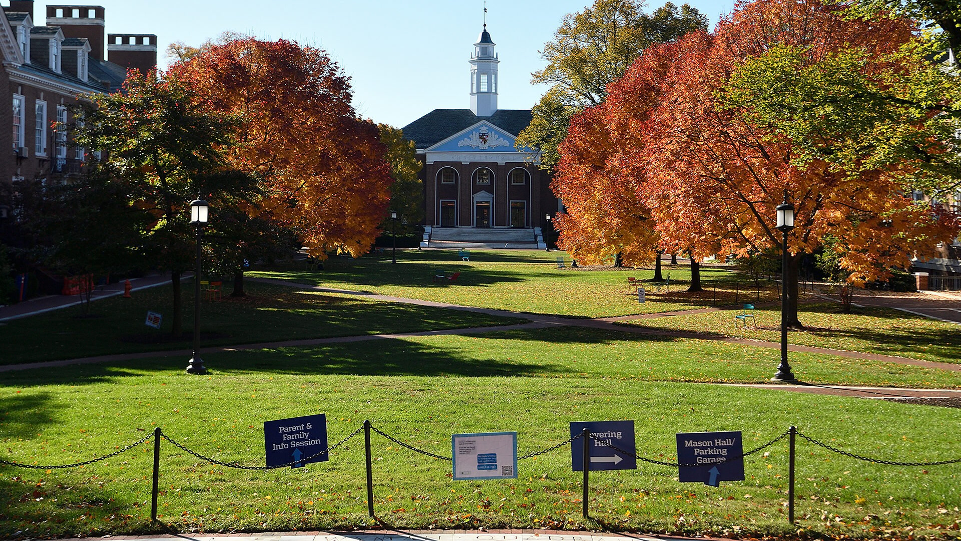 A wide shot of campus shows two buildings and lots of trees.