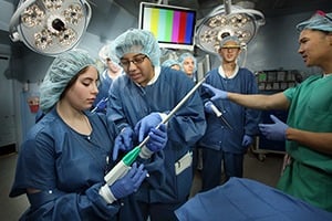 Students are working in the OR with a surgeon.