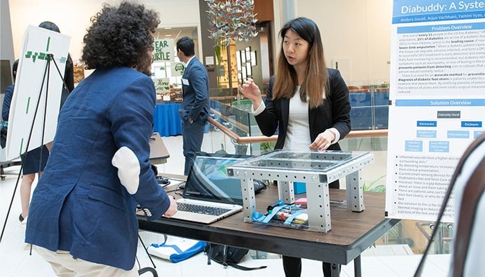 Two students are talking to each other about a prototype.