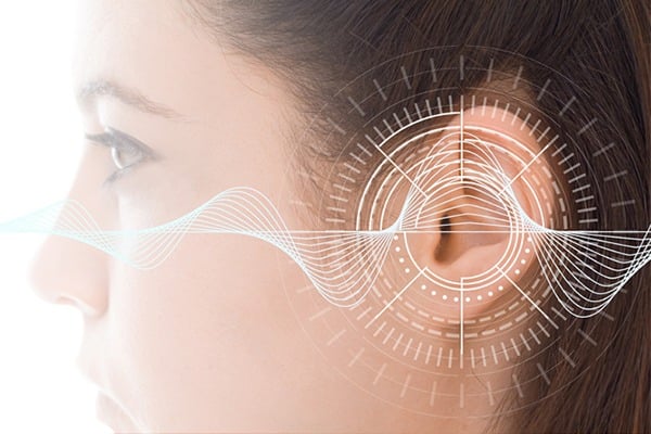 An image of a woman's ear is shown with white lines representing sound waves.