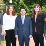 Four women and one man stand together for a photo.