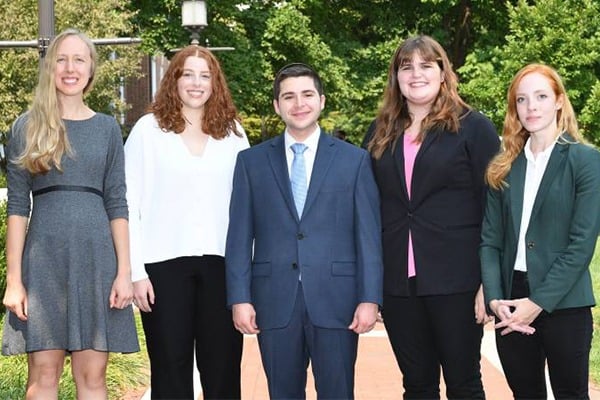 Four women and one man stand together for a photo.