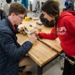 Two students are at a table working on a design project.