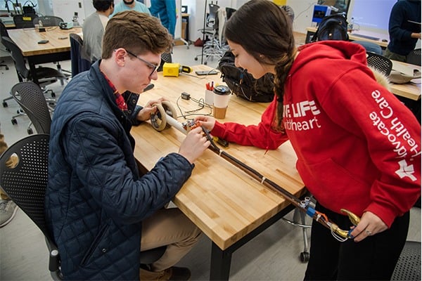 Two students are at a table working on a design project.