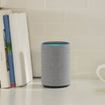 An Amazon Echo Plus sits on a counter with a mug and books.