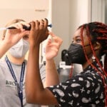 Two students are holding up and examining a pipette.