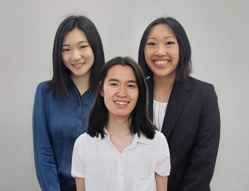 The three students stand together looking at the camera.