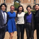 A group of students dressed in business attire are standing for a photo.