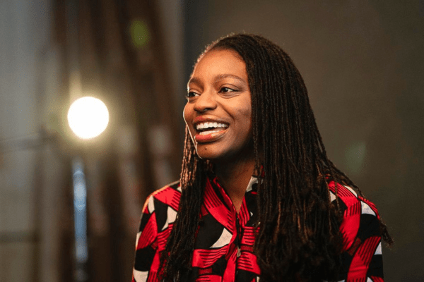 Erika Moore smiling with a bright spotlight behind her.