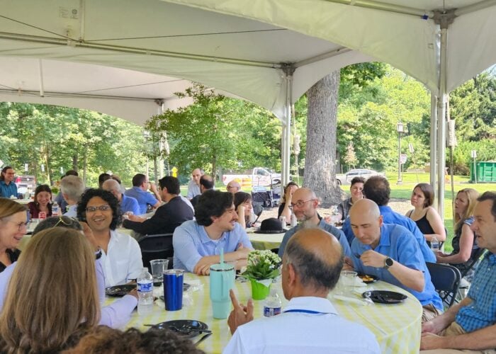 A group of people are gathering under a large tent for a picnic.