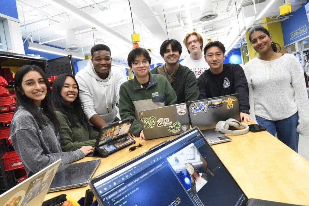 Students gathered around a table with their laptops
