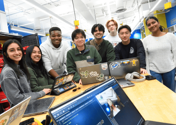Students gathered around a table with their laptops