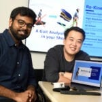 Two male students are sitting by a computer.